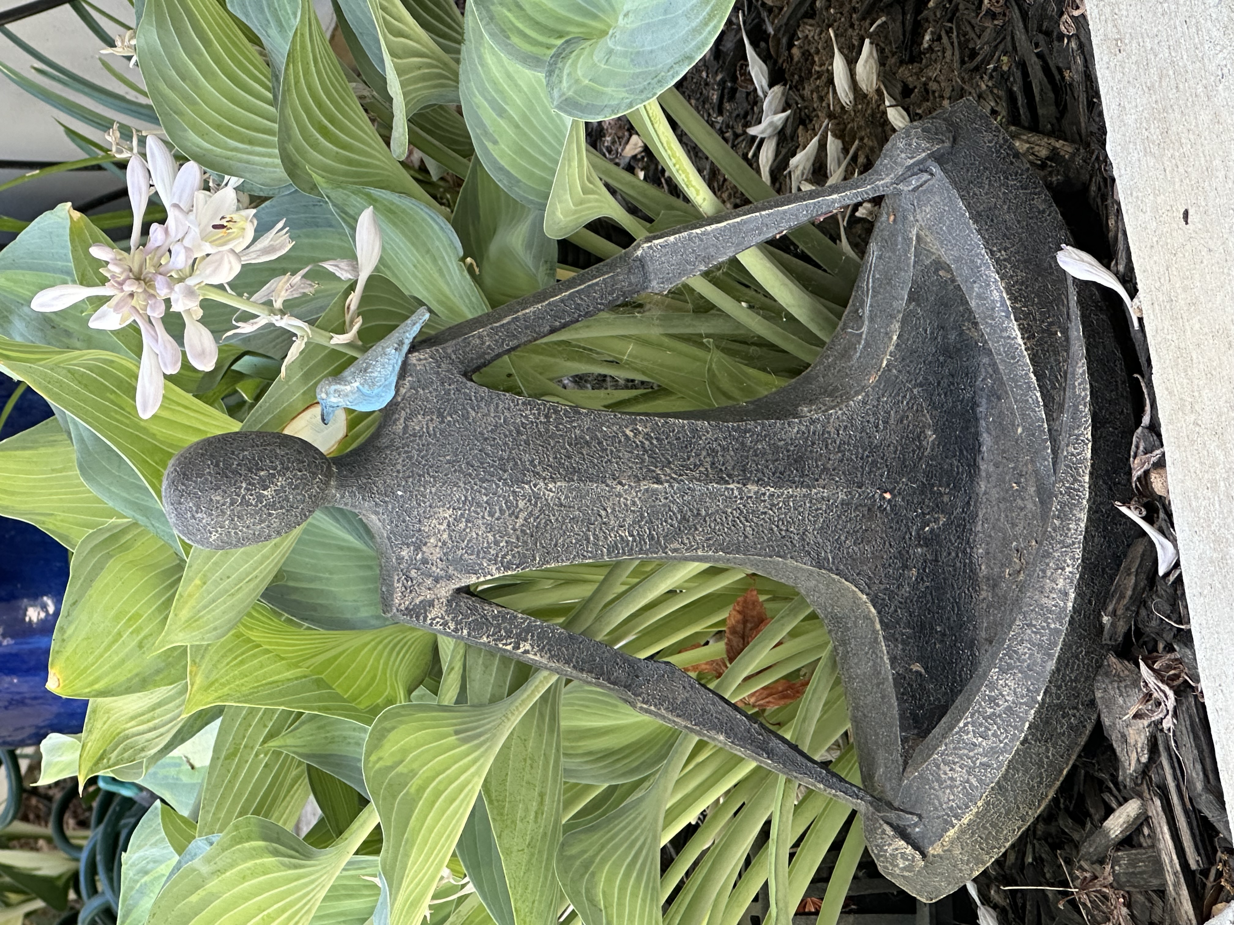 A statue of a meditating human in a garden.